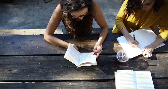 image of two people reading at a wooden table 