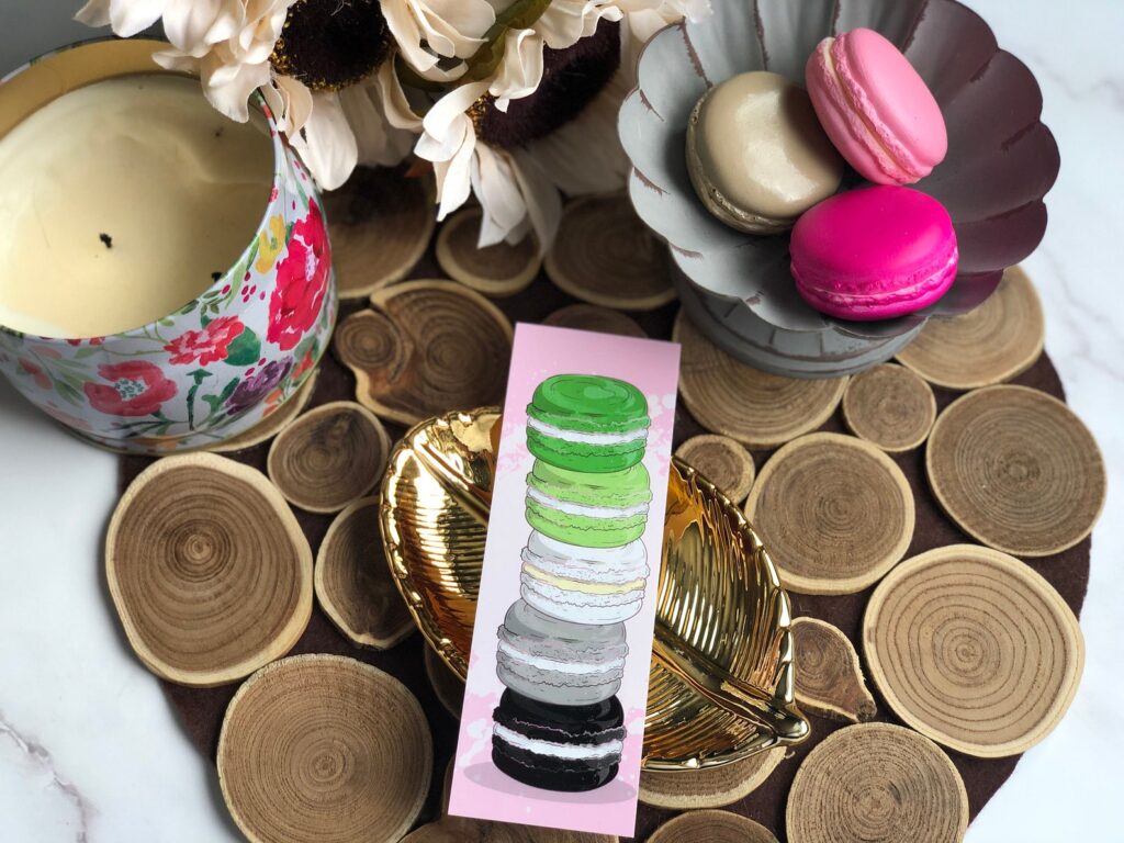 a photo of a bookmark of a stack of macarons in the colours of the aromantic flag