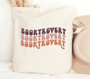 beige tote bag with "booktrovert" printed three times in muted purple, pink, orange