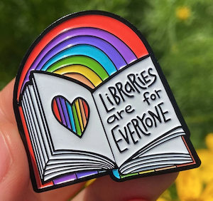 enamel pin of open book with rainbow that says Libraries are for Everyone