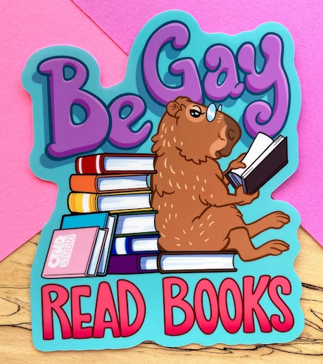 a sticker showing a capybara reading by a stack of rainbow books with the text Be Gay, Read Books