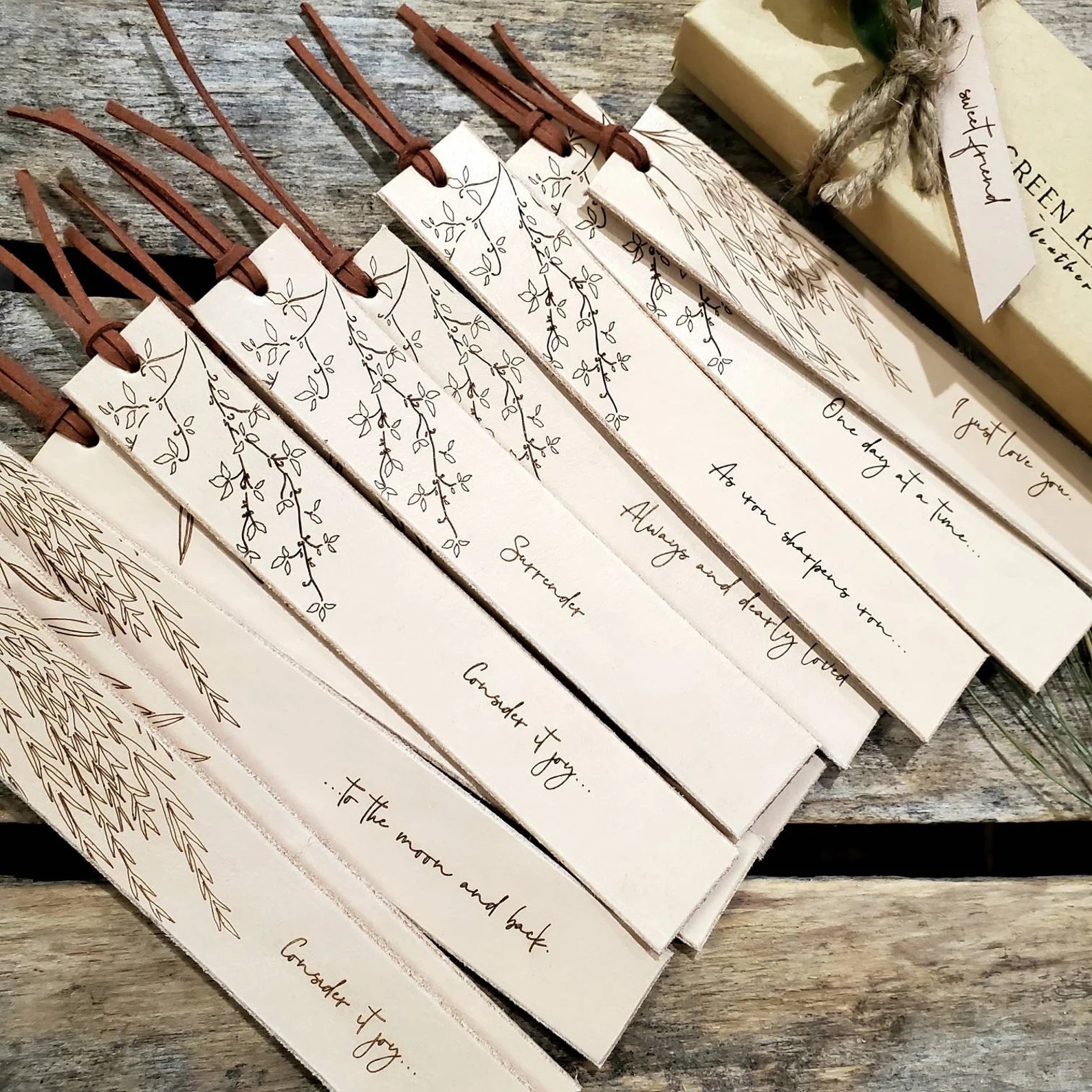 a photo of about a dozen leather book marks with tree-like patterns on them