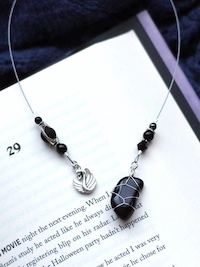 A photo of a black stone on a wire attached to a swan charm