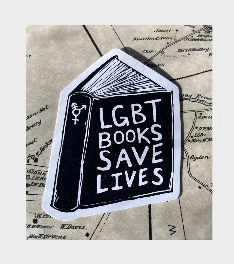 a sticker of a book with the text "lgbt books save lives" and the trans symbol