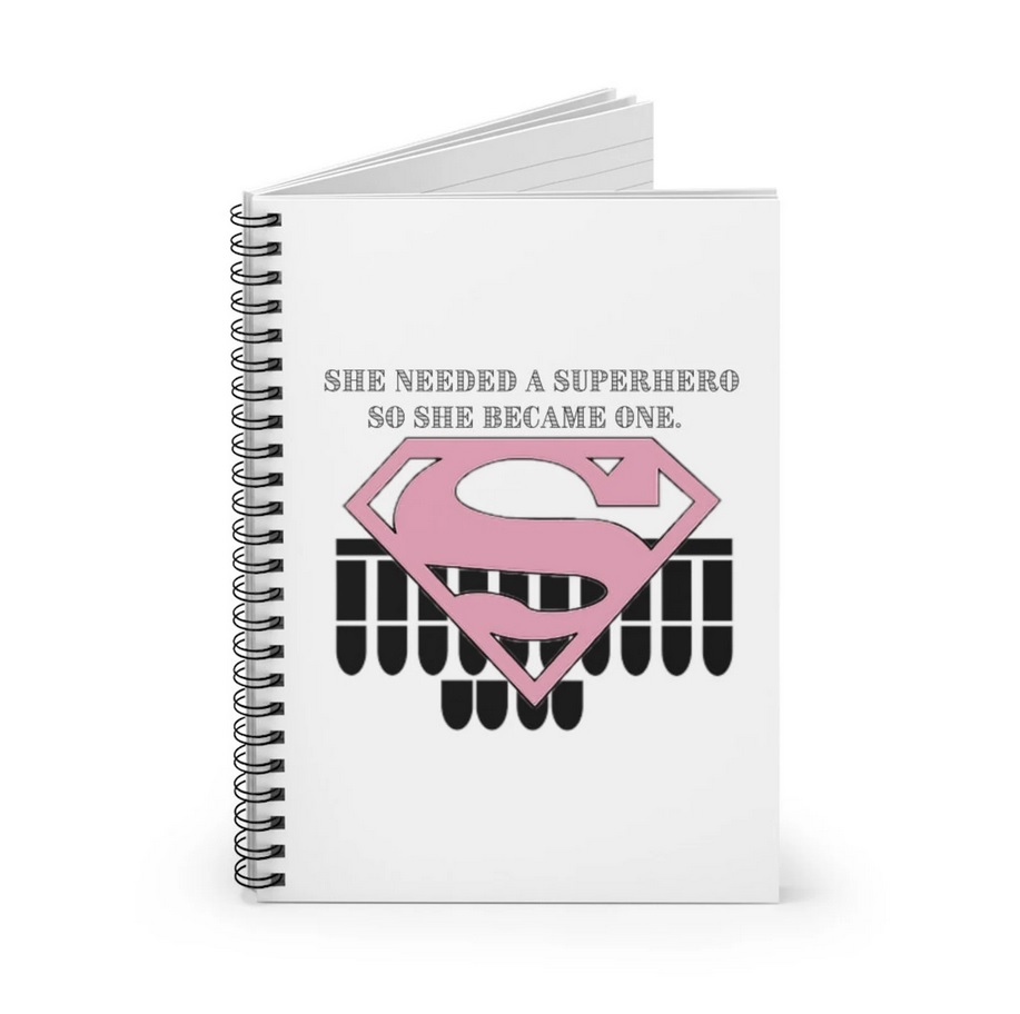 A white notebook with a pink Supergirl logo and some text on the front