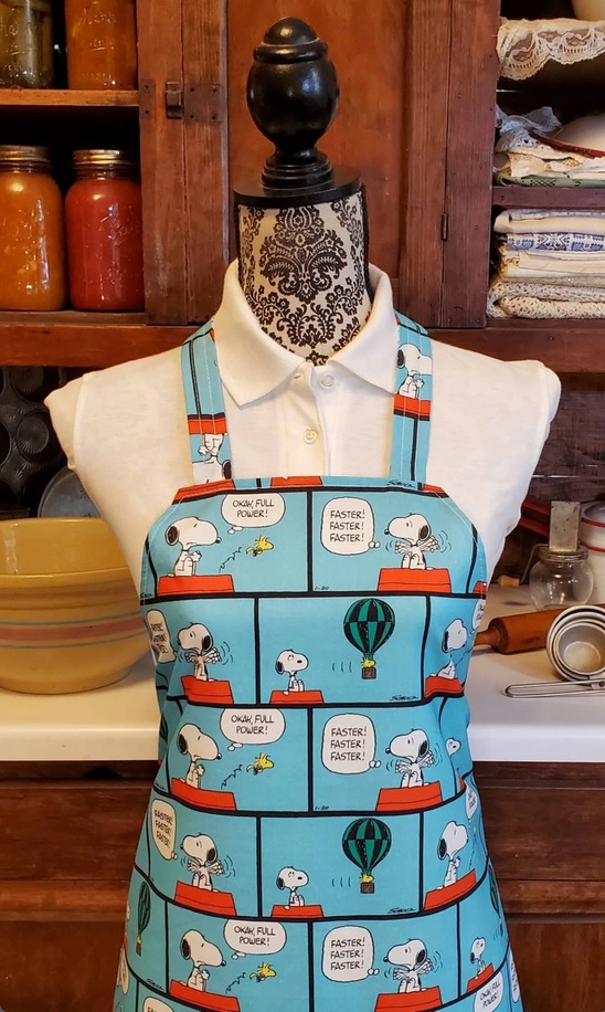 A cooking apron with a Peanuts strip pattern