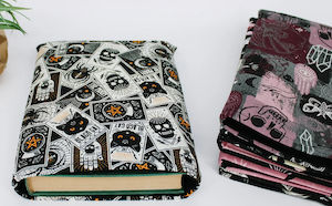 a book sleeve made of halloween printed fabric with a stack of 6 other fabric choices