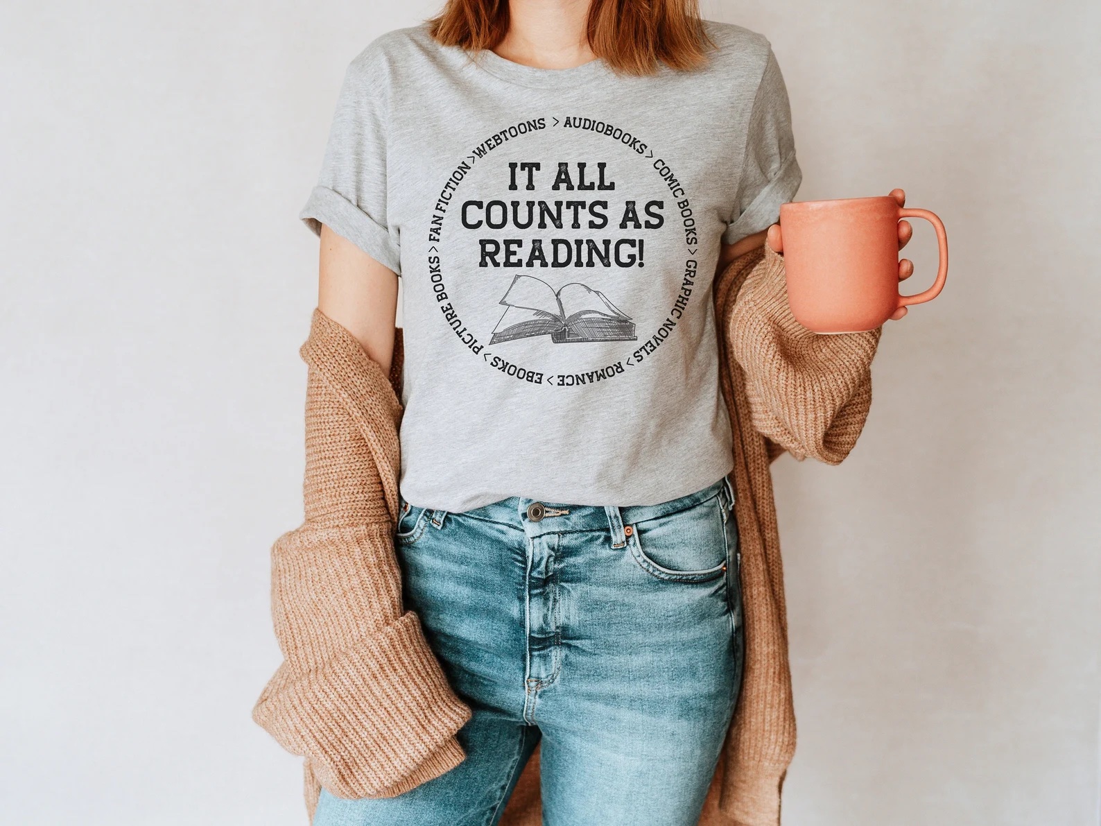 A photo of a white person wearing a gray t-shirt that says, "It All Counts As Reading!"