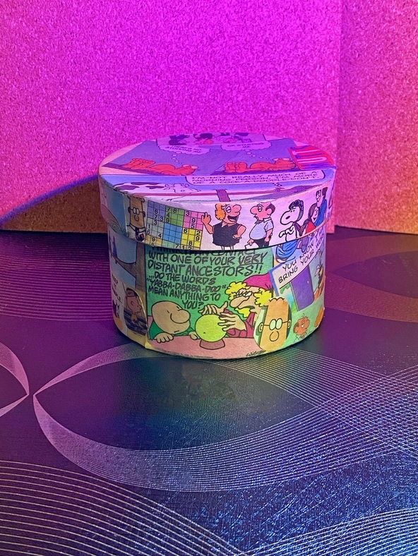 a small round box decorated with comic strips