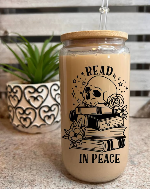clear vinyl bottle with a lid, black writing on the outside says Read in Peace with a skull and roses sitting on top of a pile of books