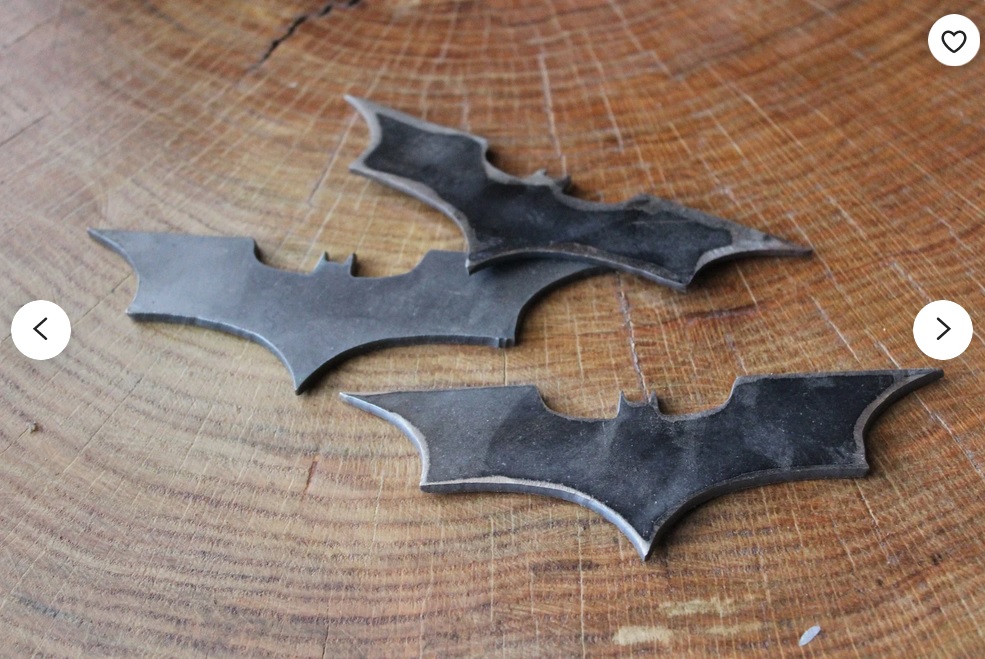 Three metal batarangs lying on a wooden surface