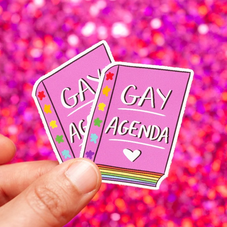 a photo of stickers of rainbow books with Gay Agenda on the cover