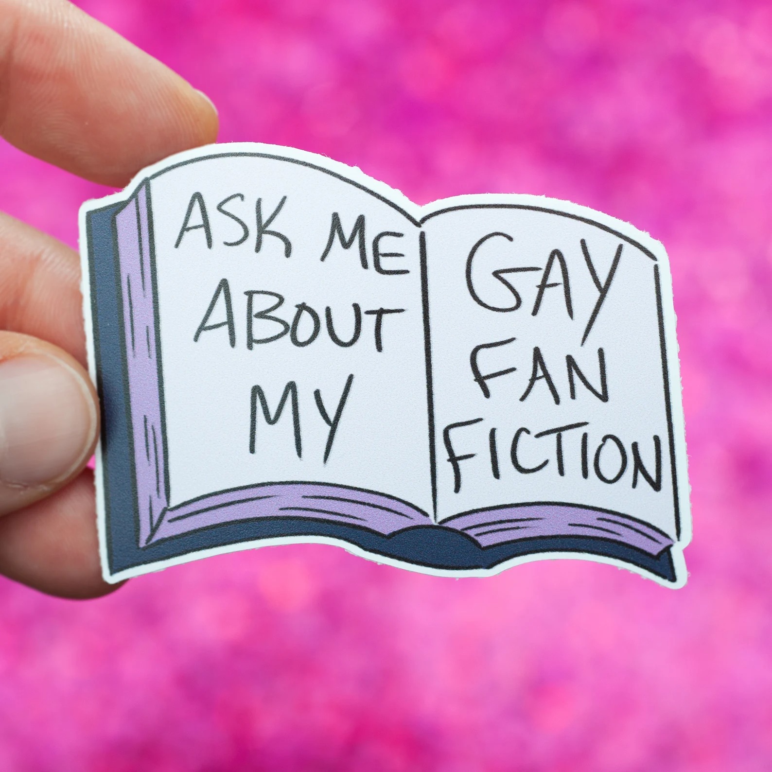 a sticker of an open book with the text "Ask me about my gay fanfiction"