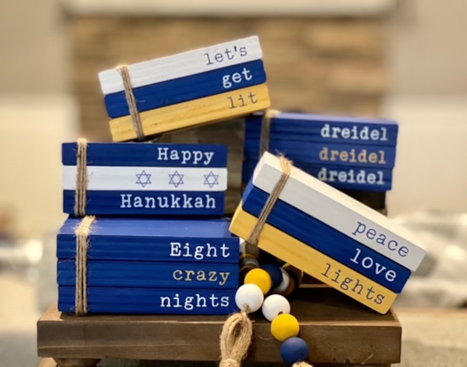 A photo of various tiny wooden books in Hanukkah colors with a bunch of corny but cute Hanukkah phrases