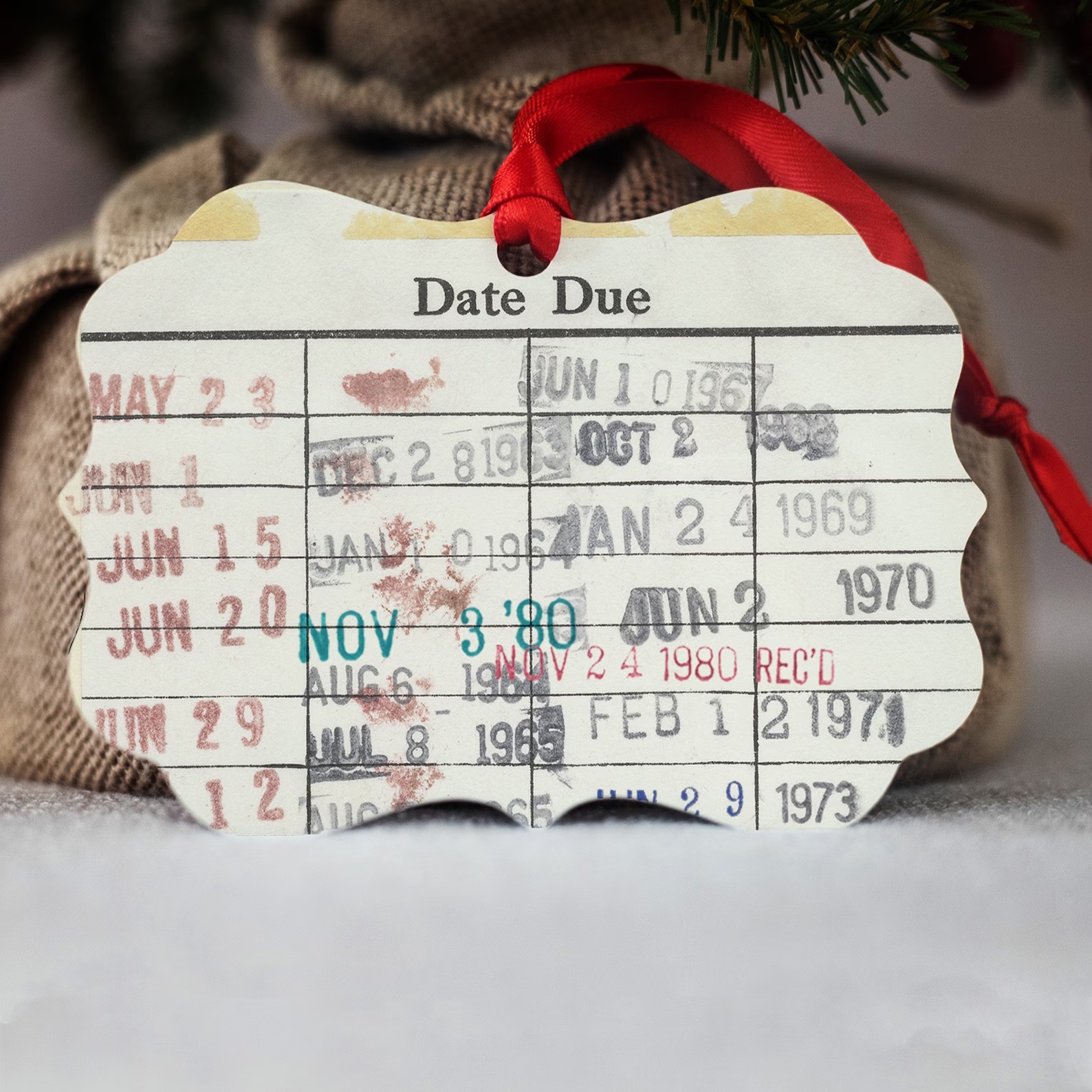 A photo of a ornament in the shape of a used library card full of stamps