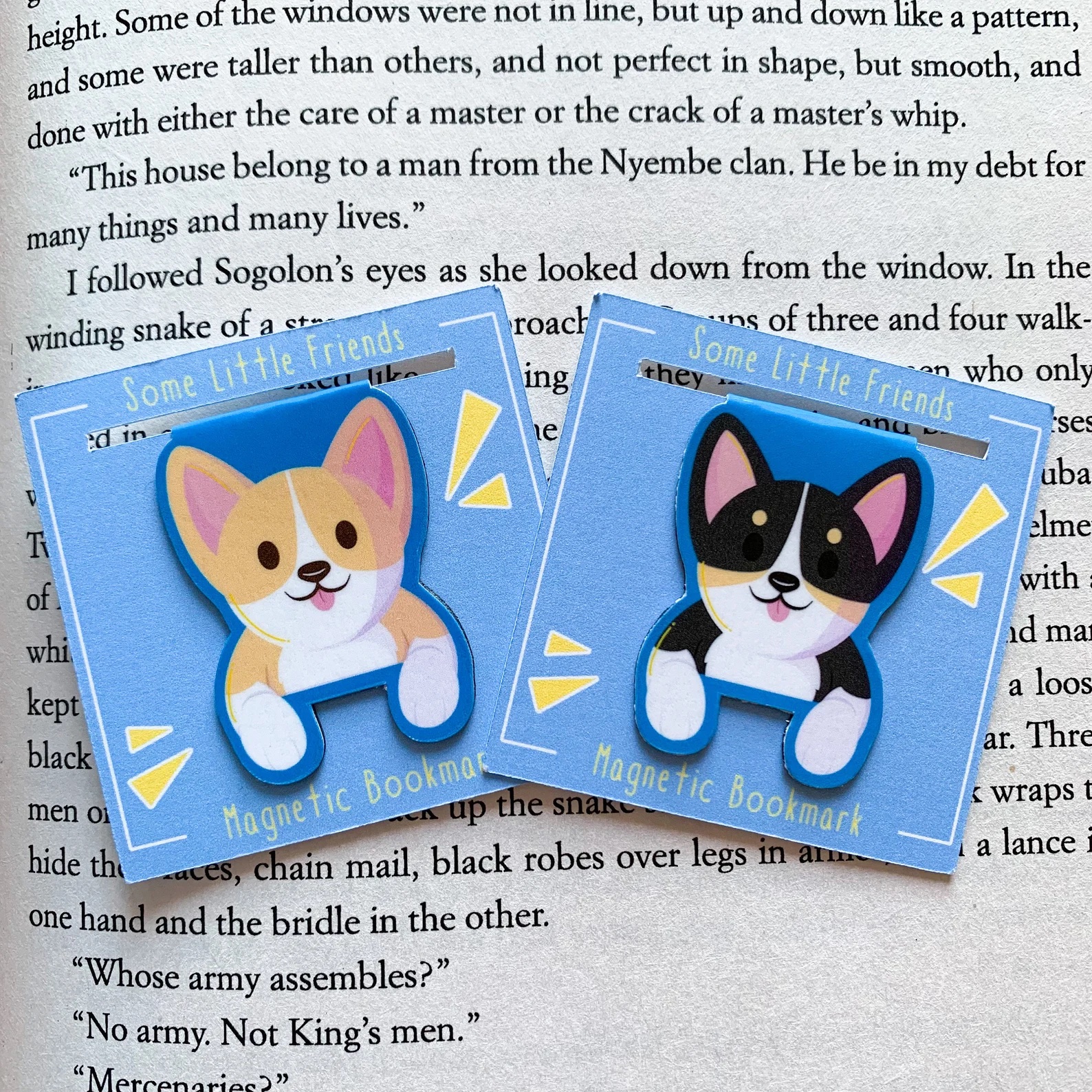 a photo of two Corgi bookmarks. This look like they are holding down the page for you. The left one is a red and white Corgi and the left is a black-headed, try-color Corgi.