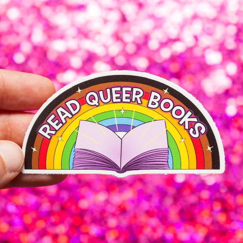 a rainbow sticker with an open book design and the text Read Queer Books