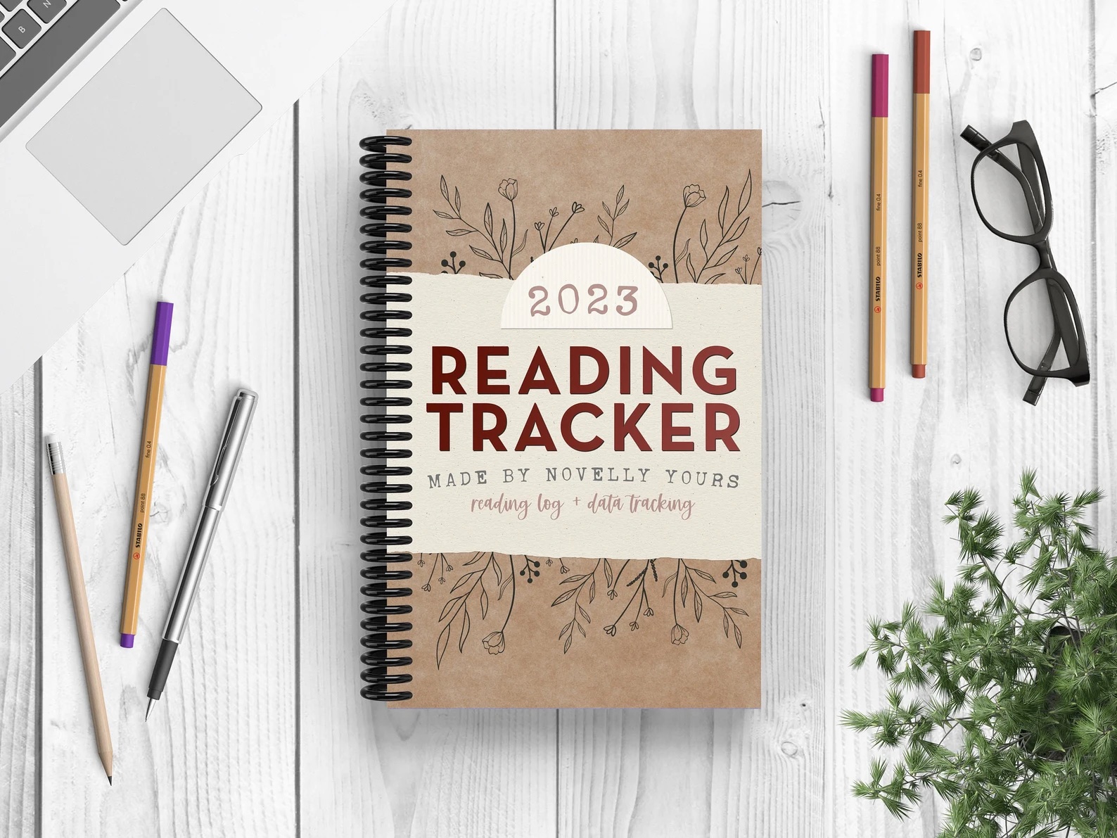 a photo of a brown notebook with an off white cover that says "Reading Tracker" in dark red