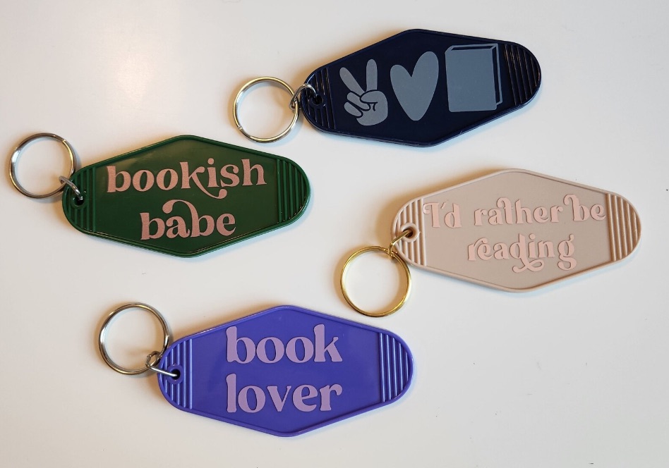 four bookish hotel style keychains in a range of colors