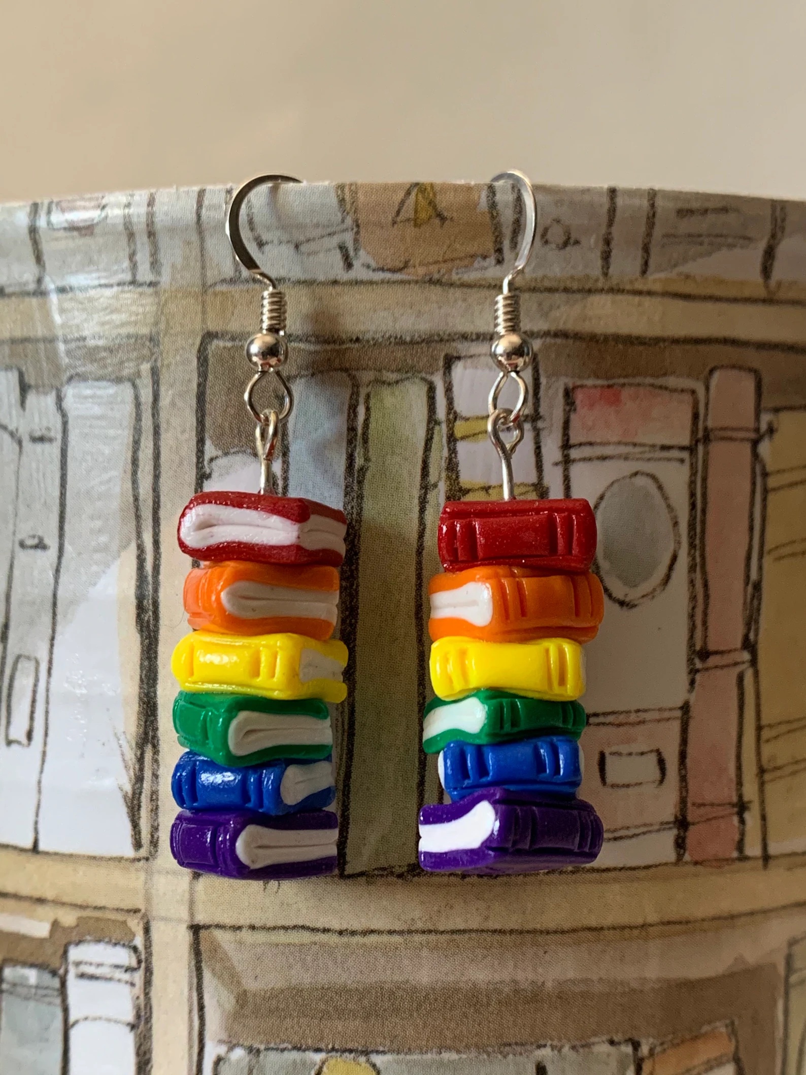 a photo of earrings made up of a rainbow stack of books