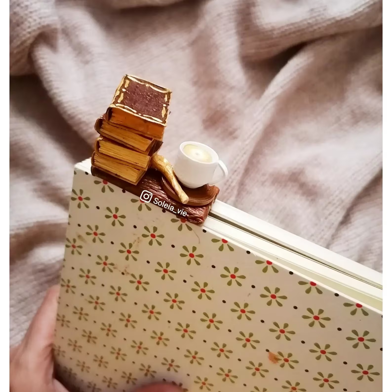 a photo of a wooden book mark featuring a carving of a stack of books and a cup of coffee