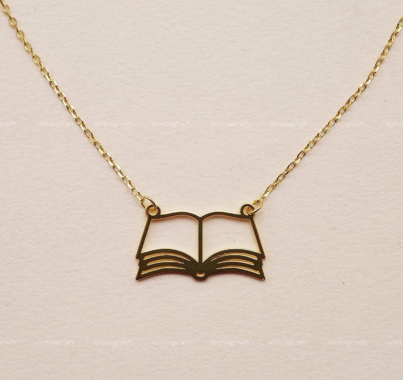 Gold necklace featuring the outline of an open book