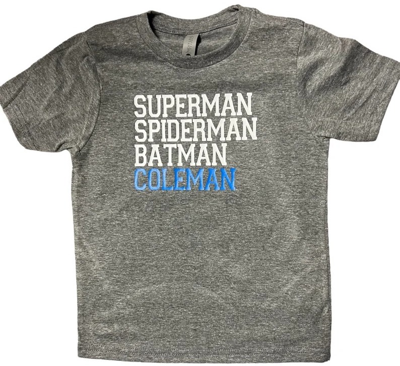 A gray t-shirt listing several superheroes and then the ordinary name "Coleman"