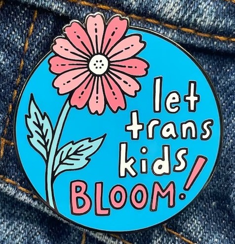 an enamel pin with the text Let Trans Kids Bloom  and a flower