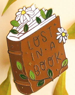 enamel pin of a book with flowers that says Lost In a Book