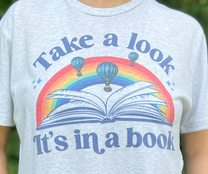 grey tshirt with open book, rainbow, and hot airballoons design that says "take a look it's in a book"