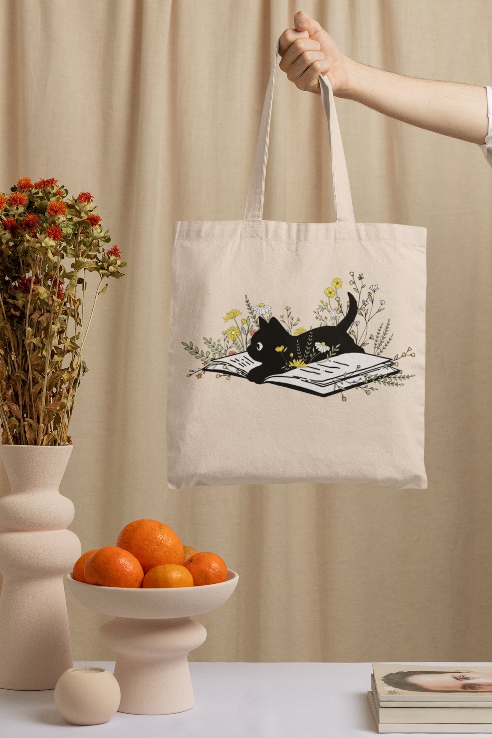 a photo of a tan tote bag featuring a black cat on a book