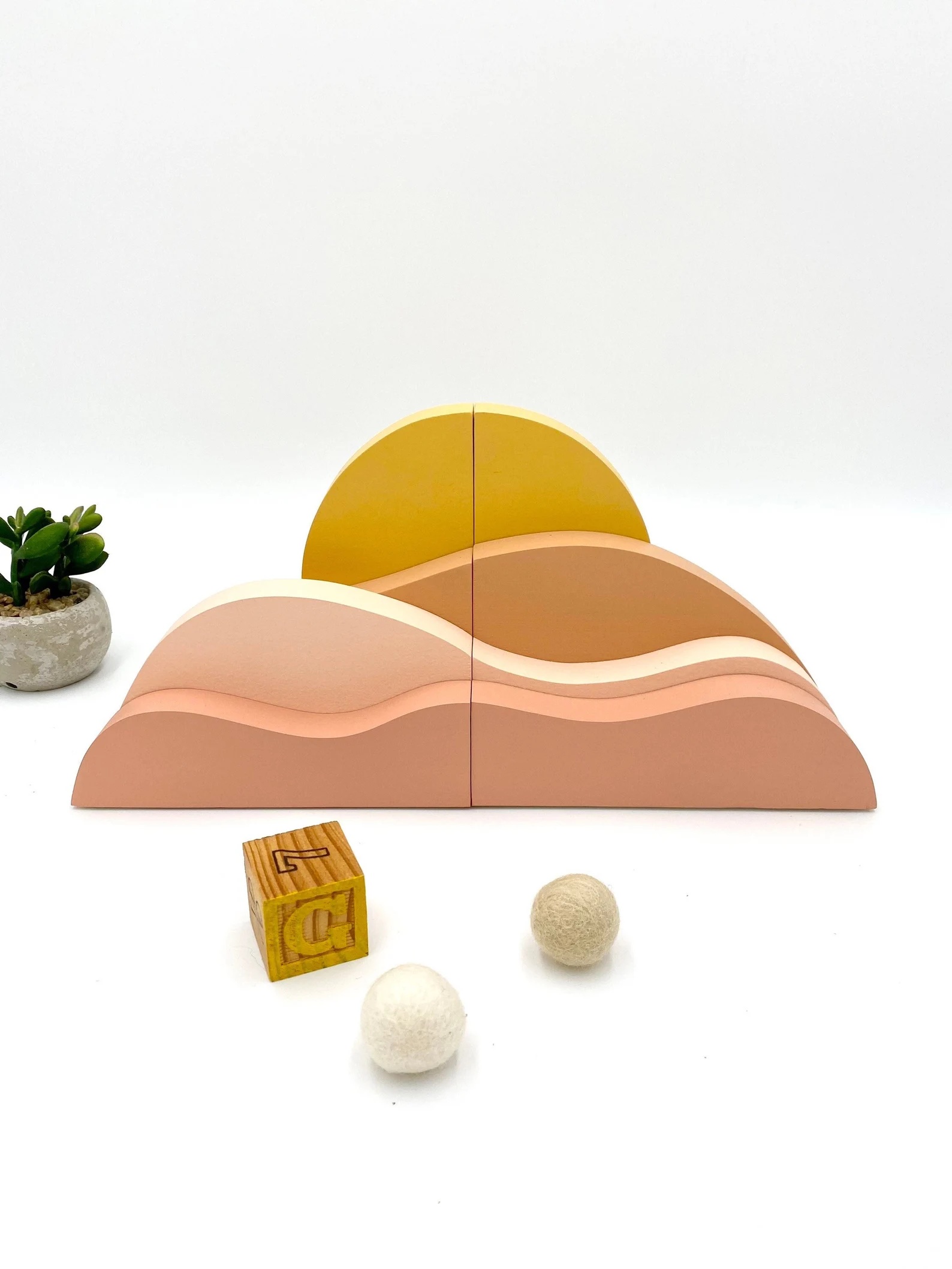 a photo of a set of wooden bookends that, when pushed together, depict a pink and orange sunrise