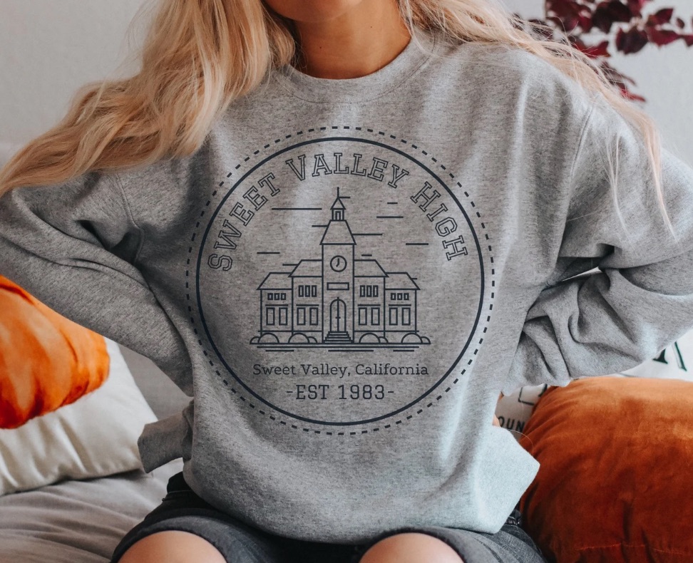 Image of a person wearing a gray sweatshirt. The shirt has a made up logo for Sweet Valley High School. 
