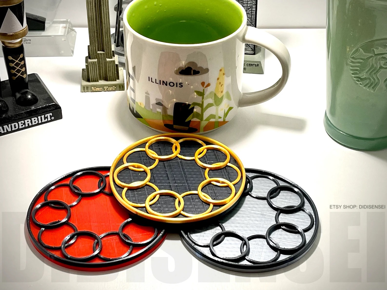 Three coasters of different colors, each with a design evoking the Ten Rings