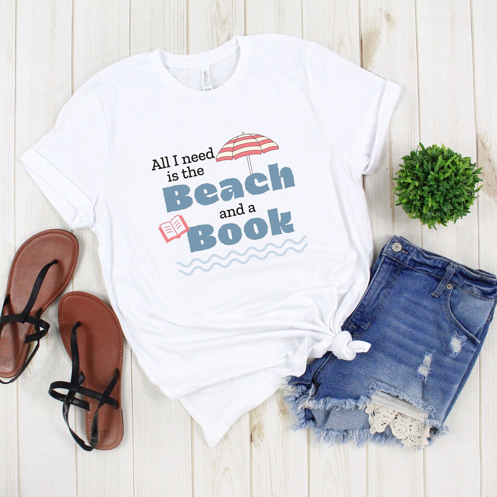 a photo of a white t-shirt that says, "All I need is a beach and a book."