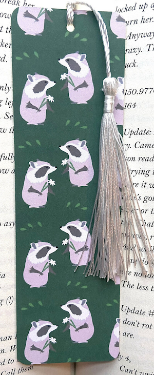 green bookmark with graphic design print of pink raccoons holding a flower