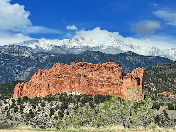 snowy mountain in the background, with a large red sandstone rock formation in the foreground