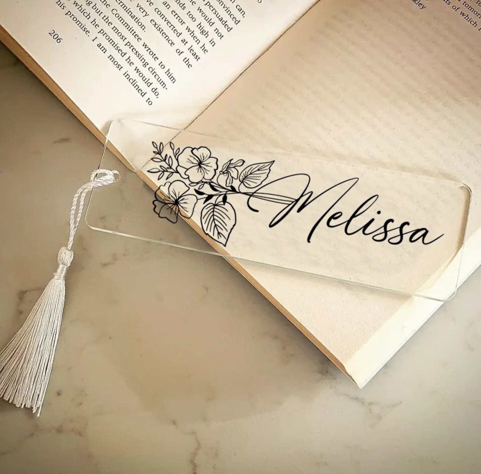 a photo of a clear bookmark featuring a black outline of a flower with the name Melissa in cursive