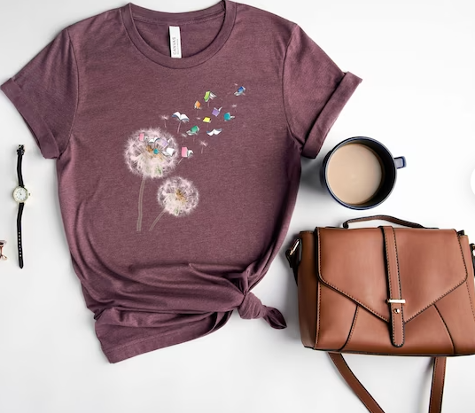 Dandelion Books Shirt, a cup of coffee, a brown satchel, and a black wristwatch