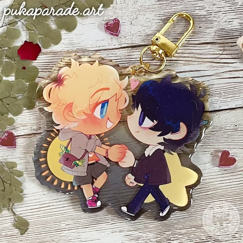 a photo of a keychain charm of chibi  Will Solace and Nico DiAngelo holding hands