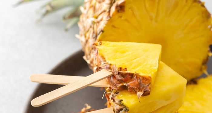 cut pineapple, and quartered pineapple cuts on popsicle sticks