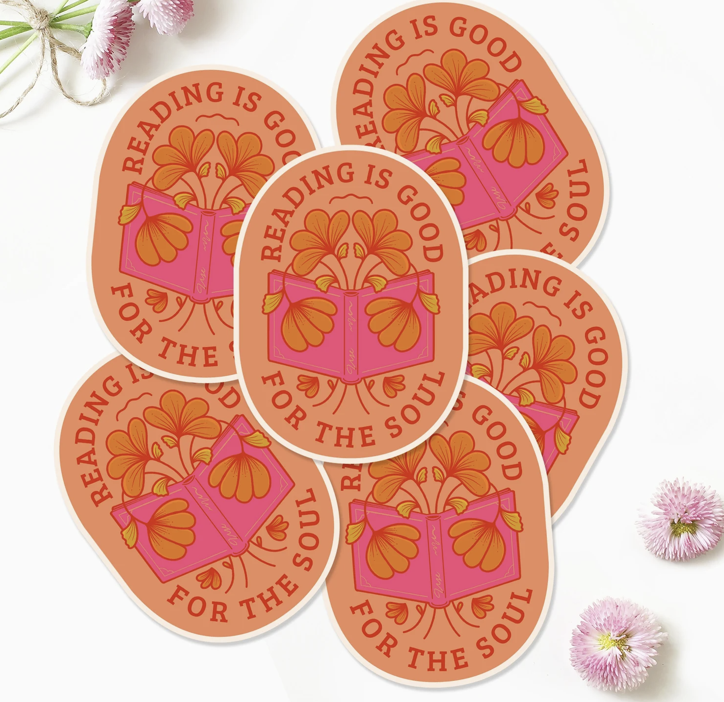 Peach oval sticker decorated with a pink book and surrounded by orange flowers with the words "Reading is good for the soul" around the edges.