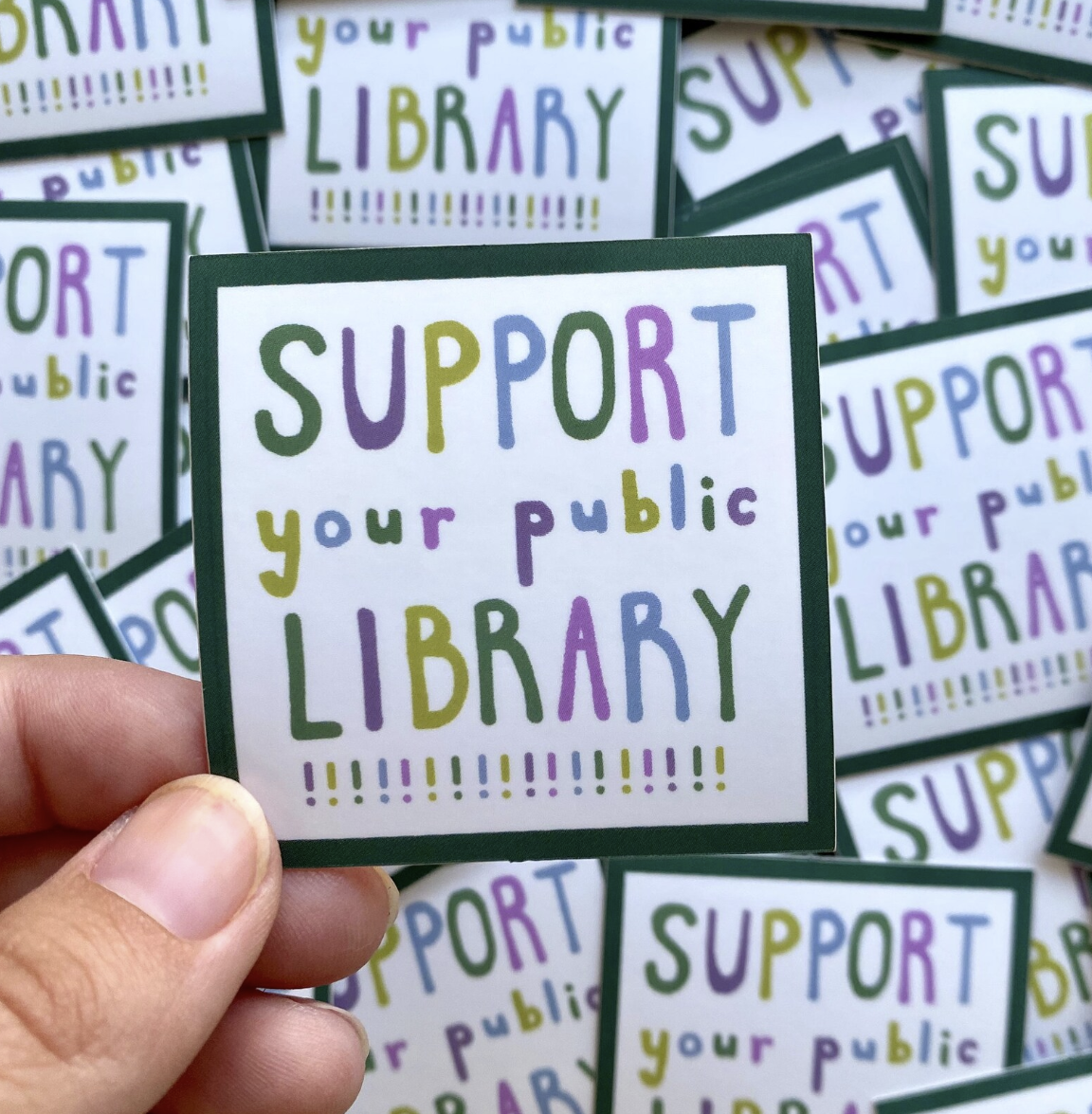 Square sticker with multi-colored text reading "support your public library!!!!!!!!!!!!!!!!!" surrounded by simple black border