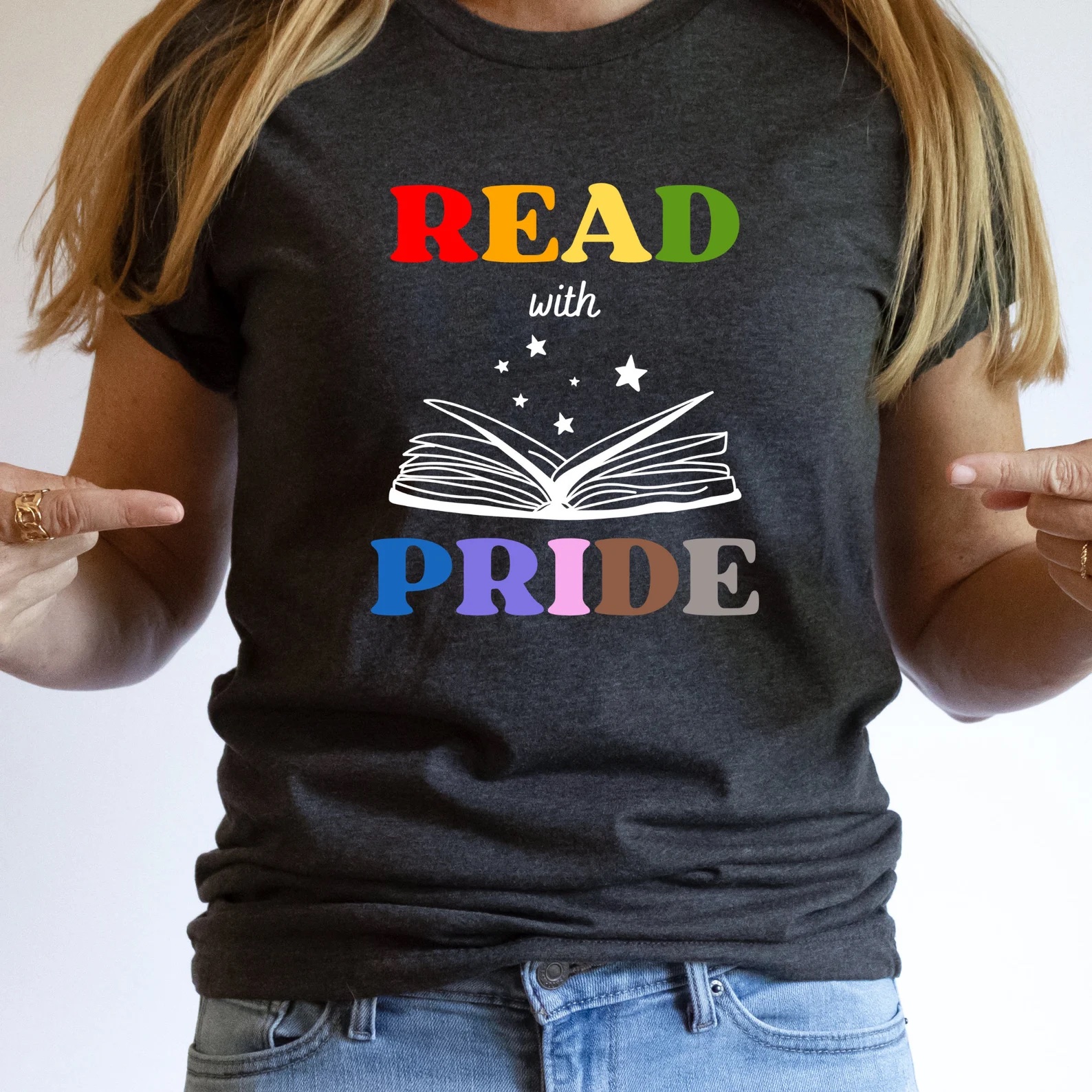 a photo of a dark gray t-shirt with a white outline of an open book. the words "read with pride" are in rainbow colors