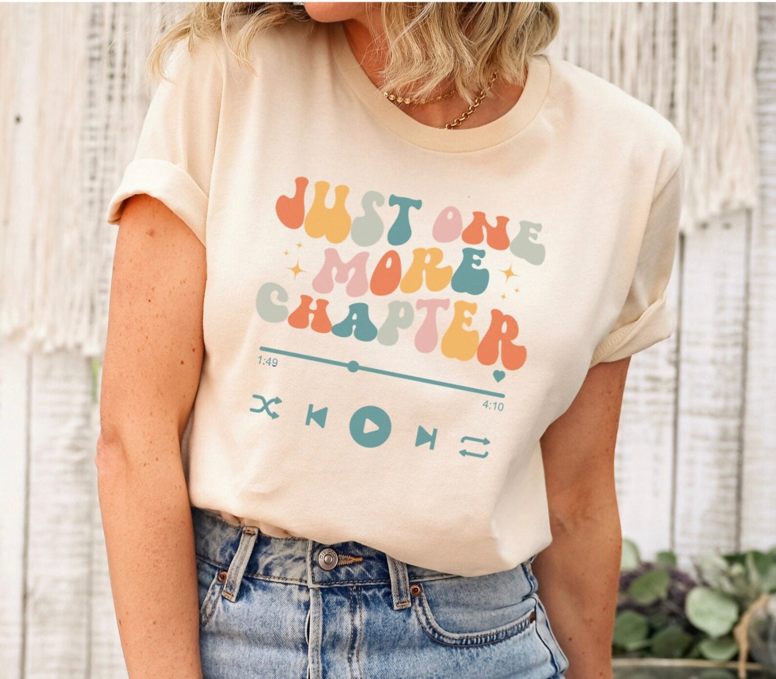 a photo of a t-shirt that says, "Just one more chapter." An illustration of a play bar are under the words.
