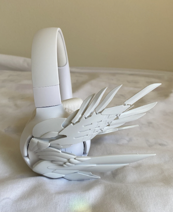 a photo of white headphones with white mecha-like wings on the sides