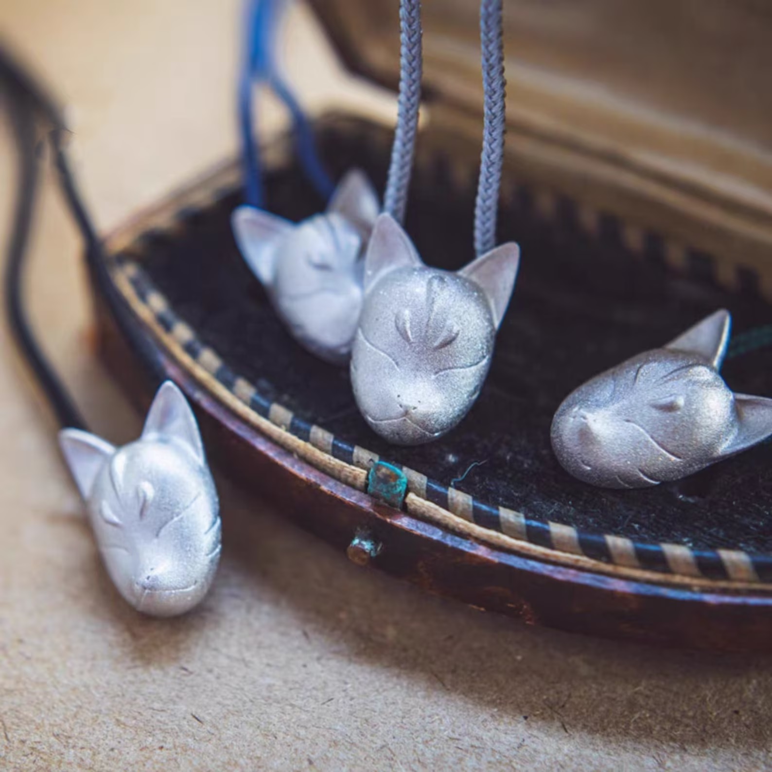 Silver fox pendants sit in and around a small, dark box