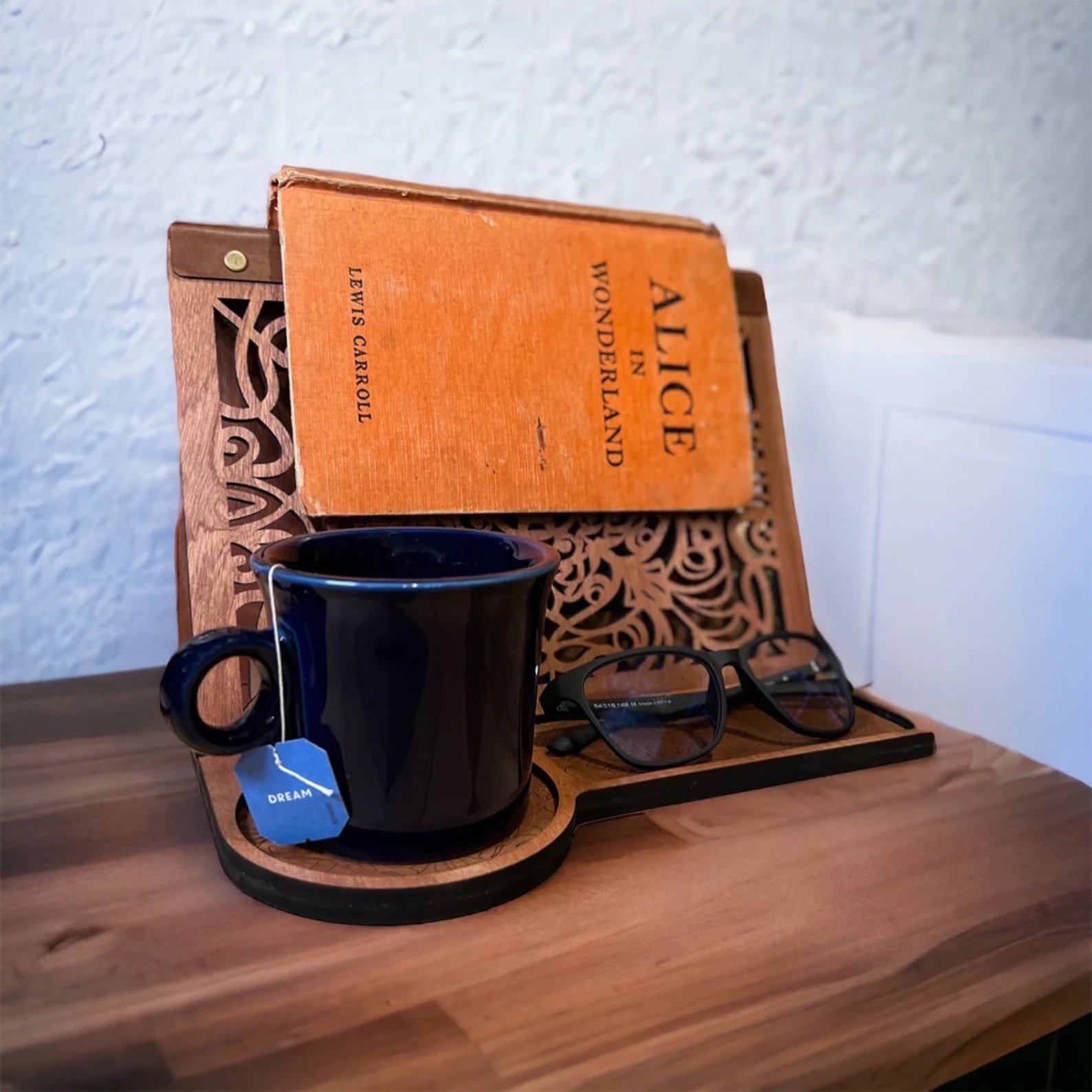 a photo of a wooden book stand that features places for a mug and a pair of glasses