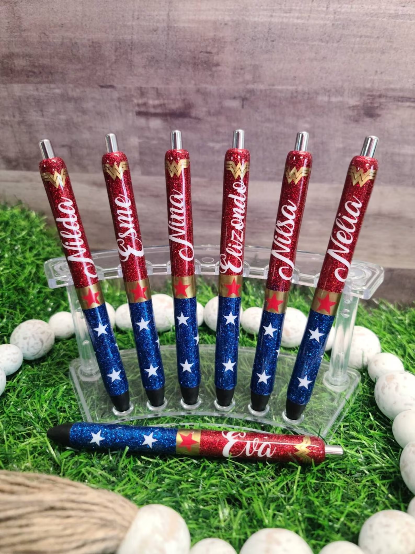 A selection of seven pens, each with Wonder Woman's colors and a different name in white cursive