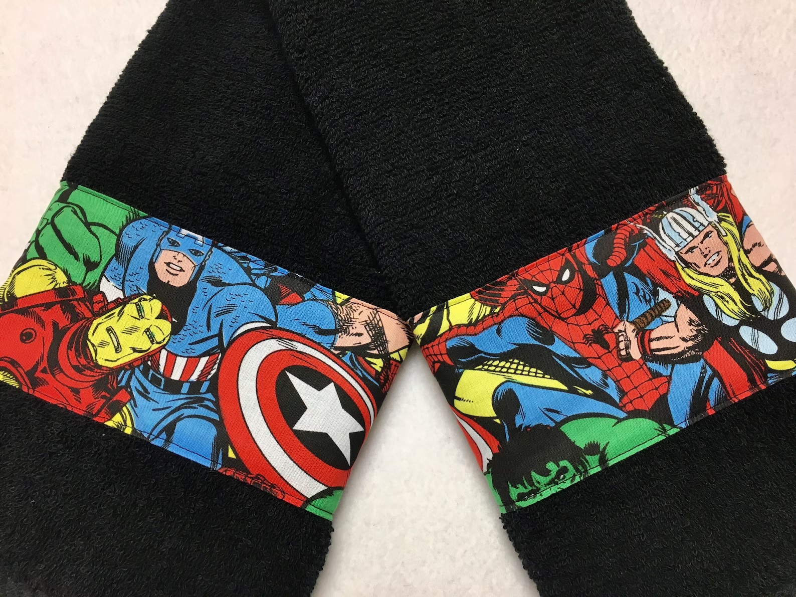 Two black towels, each with a band featuring Marvel superheroes